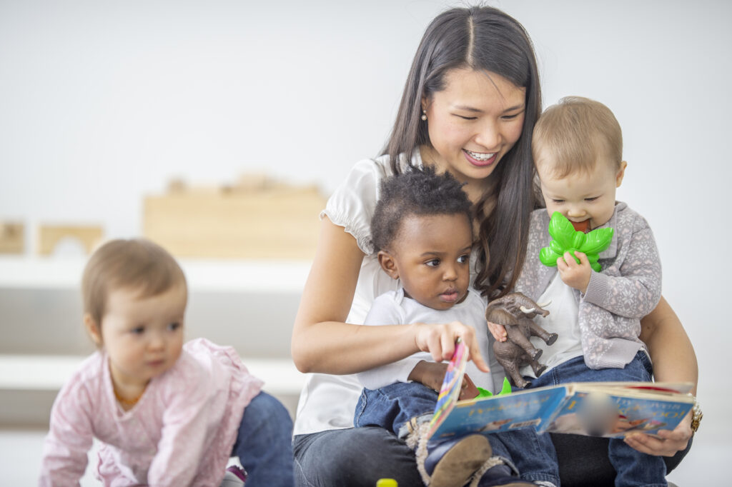 Preschool teacher reads a book to her students
