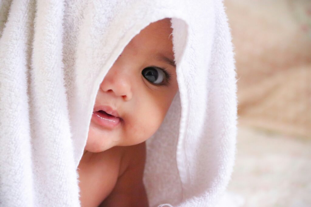 Baby looking out from behind a towel