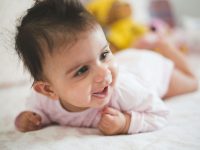Baby smiling on mat for tummy time