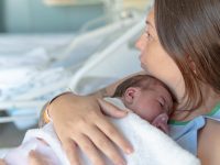 Mother holding baby close to her chest after delivery