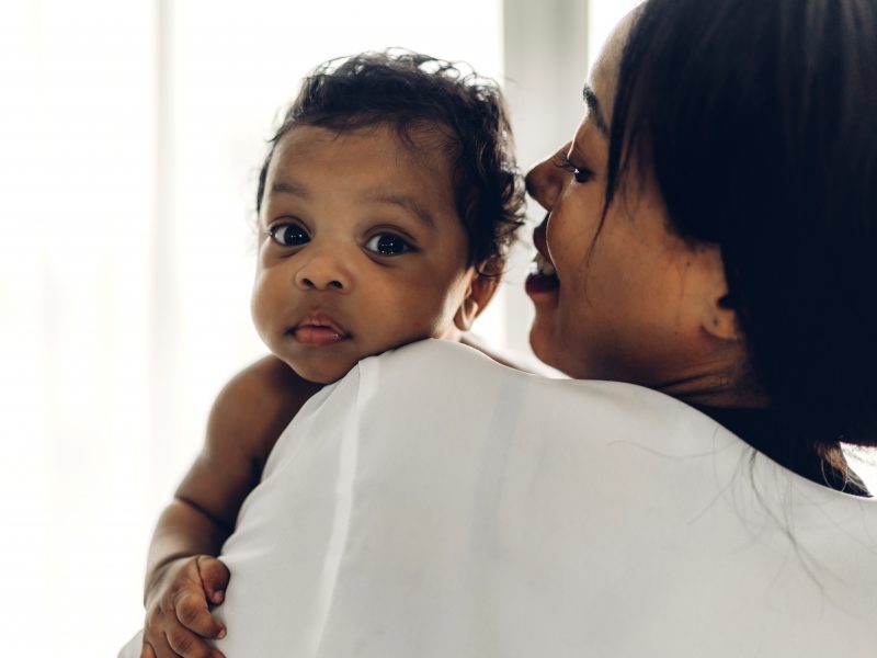 Mother holding baby in her arms in bedroom.