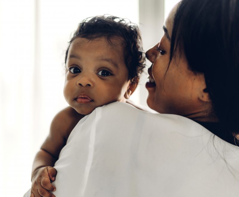 Mother holding baby in her arms in bedroom.