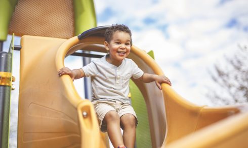 Happy 3 years old boy on a swing. Happy kid on playground